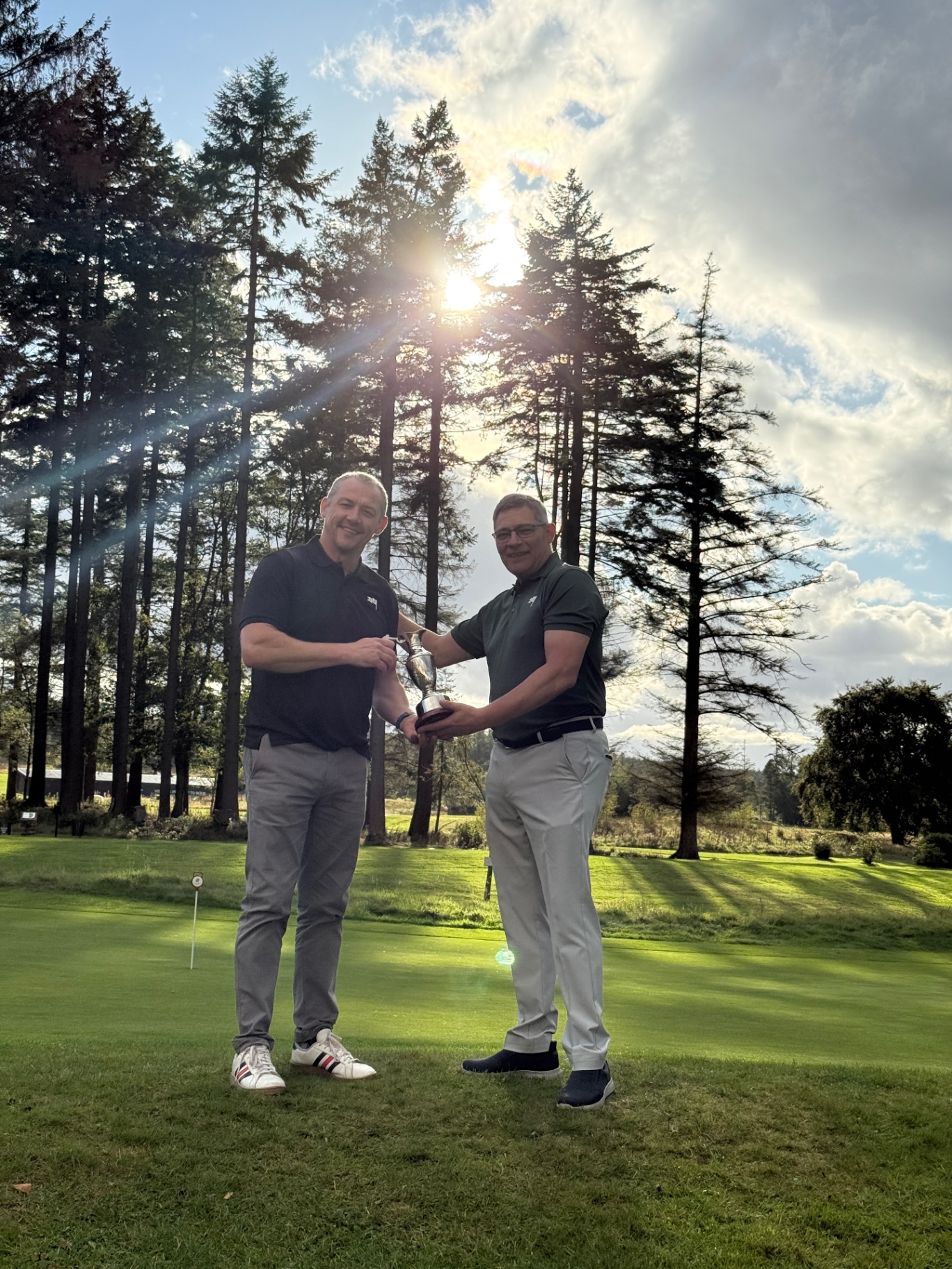 Two players raising the Jimmy's Jug trophy at sunset